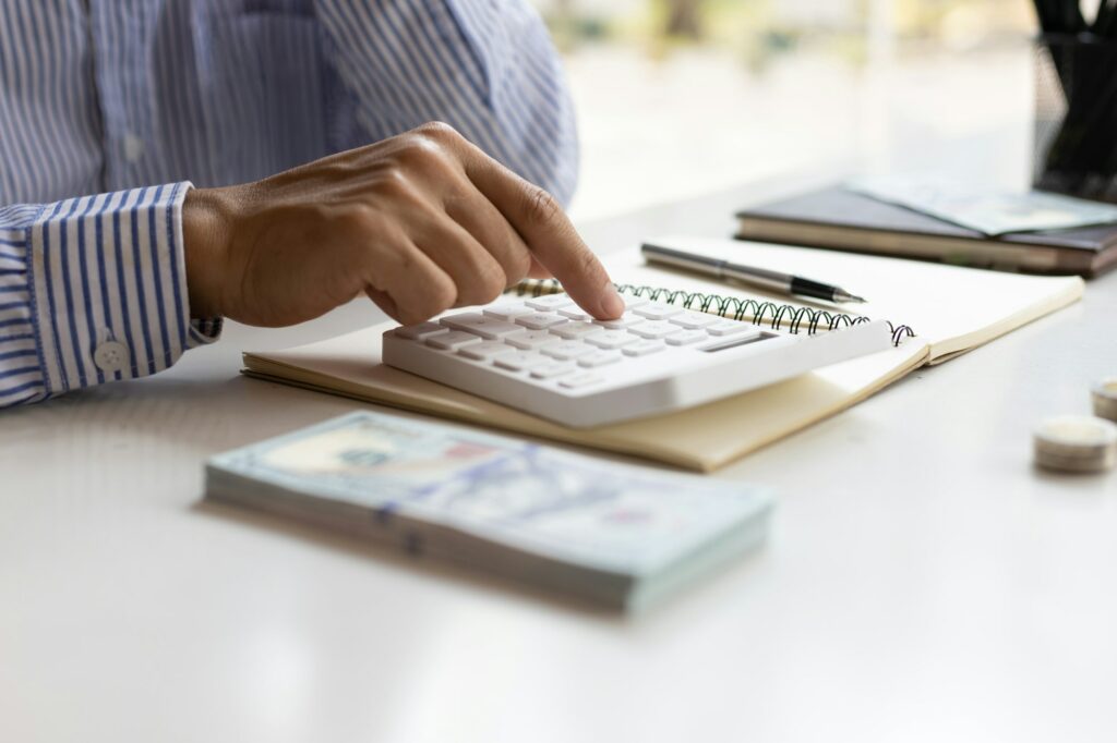 Businessman using calculator calculating income and expenditure for bookkeeping.